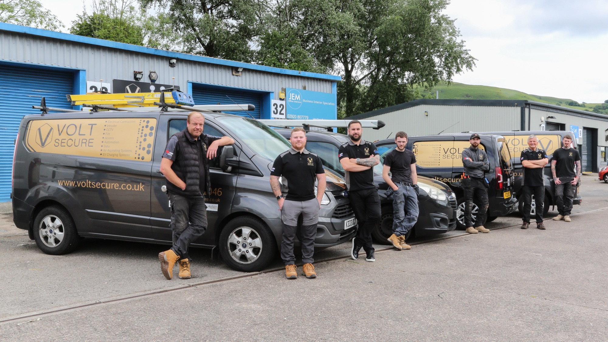 The VoltSecure engineering team lined up with branded vans at the company depot